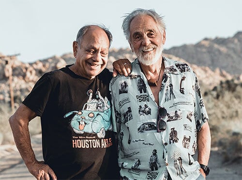 Cheech and Tommy stand together smiling and laughing.